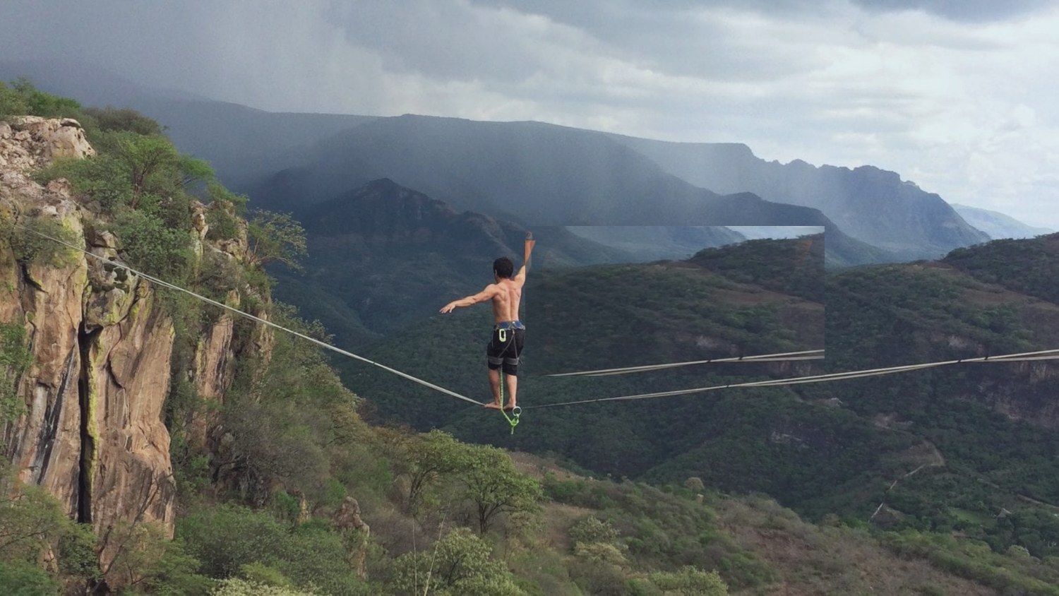 Slackliner crossing a canyon between mountains